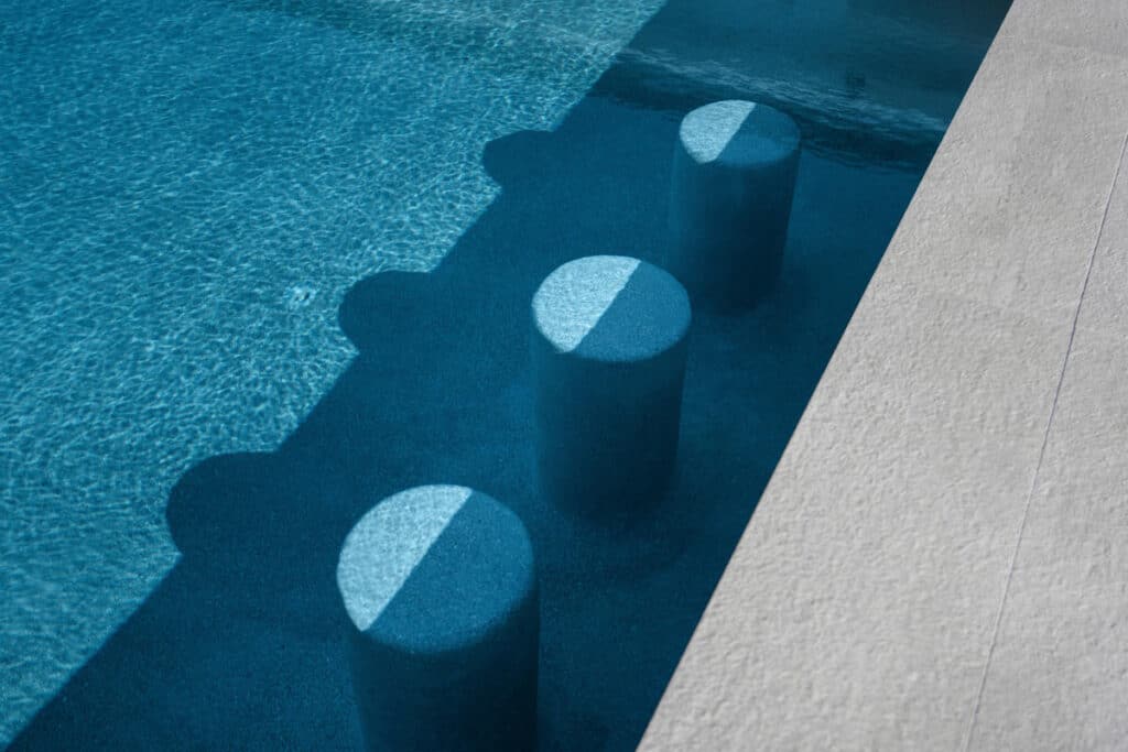 A close-up of a turquoise pool with submerged circular seating, capturing the sparkle of sunlight on water.