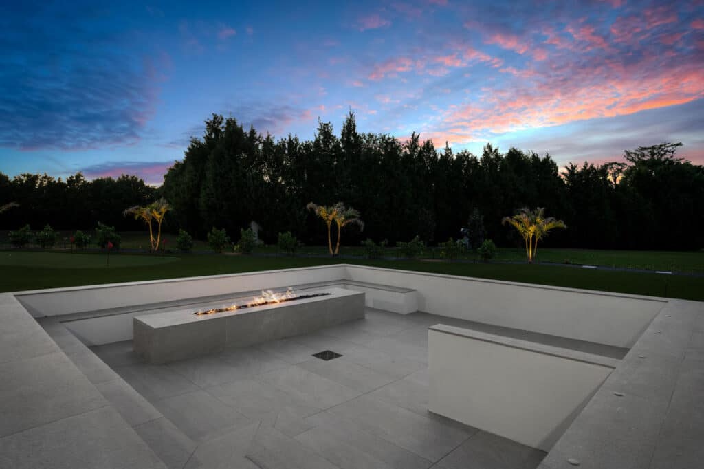 A cozy backyard fire pit glowing warmly under the twilight, surrounded by comfortable seating and modern landscaping.