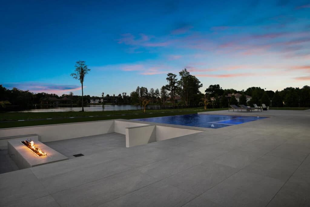 A sparkling pool with clean water and a contemporary design, complemented by a green lawn and sunny skies.