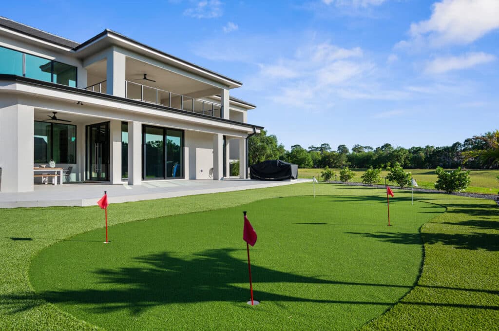 A two-story contemporary home with a backyard putting green, landscaped for luxury and recreation.